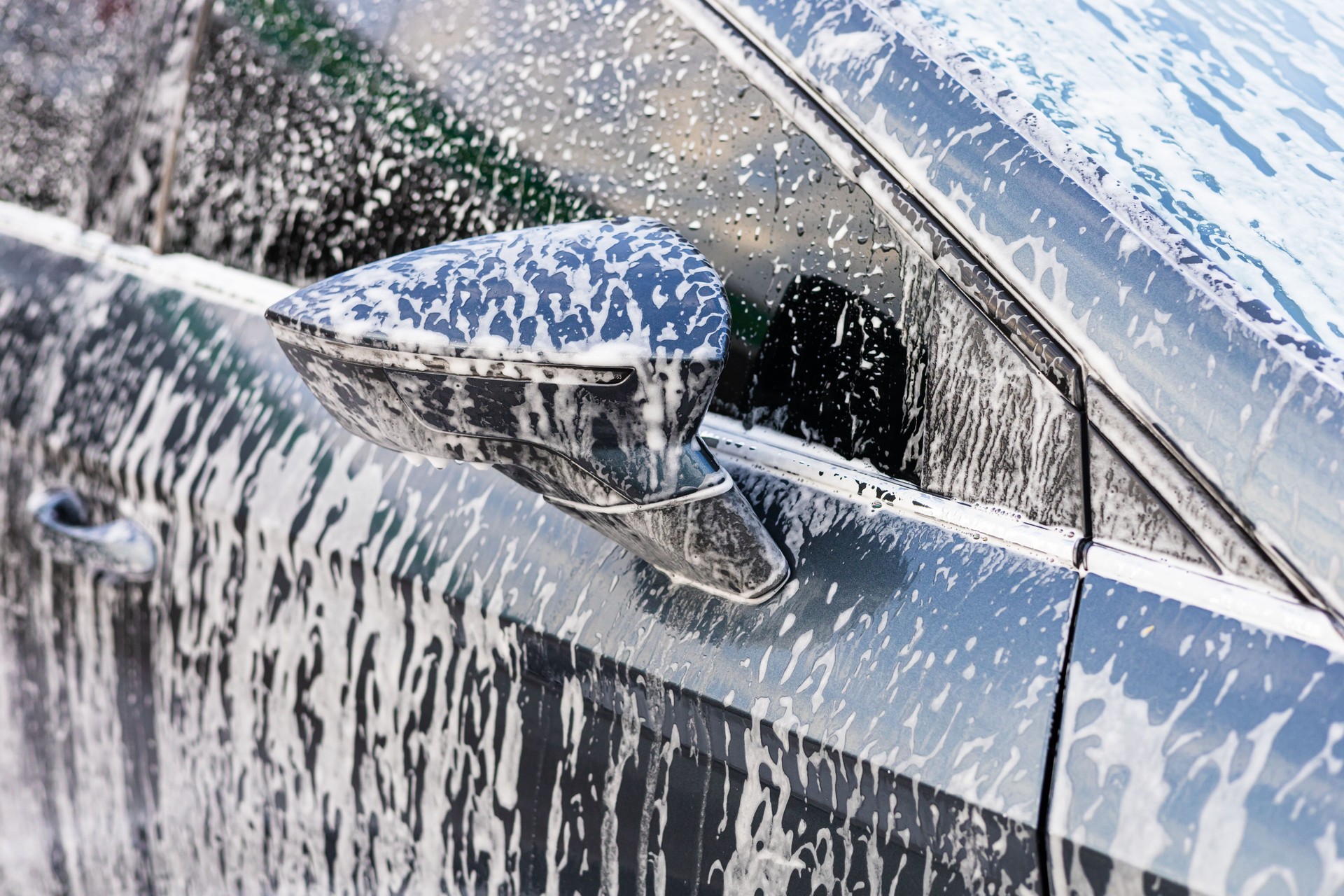 Washing a car with soap on a sunny day in a driveway near the home